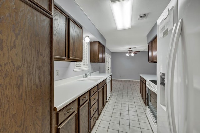 kitchen featuring dark brown cabinets, light tile floors, ceiling fan, white appliances, and sink