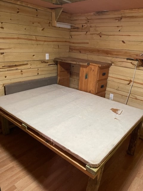 unfurnished bedroom with wood walls and light wood-type flooring