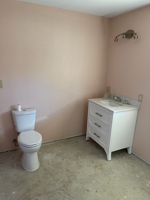 bathroom with concrete flooring, toilet, and vanity