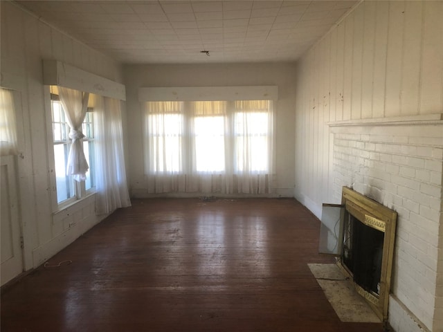 unfurnished living room with a brick fireplace and dark wood-type flooring