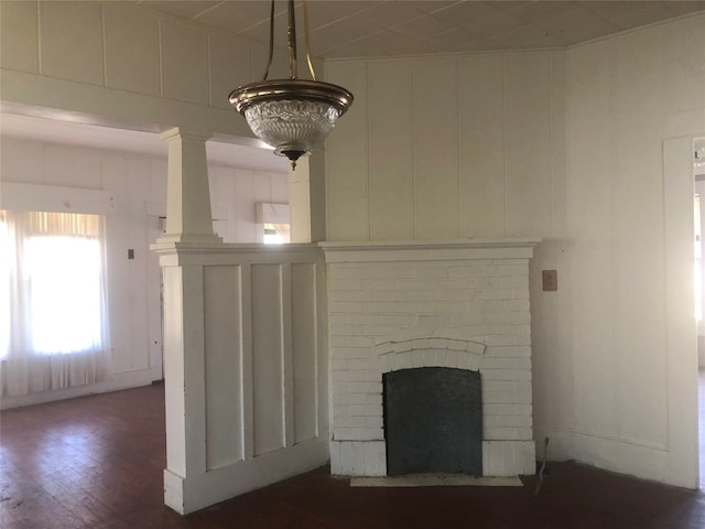 unfurnished living room with brick wall, a brick fireplace, and dark hardwood / wood-style flooring