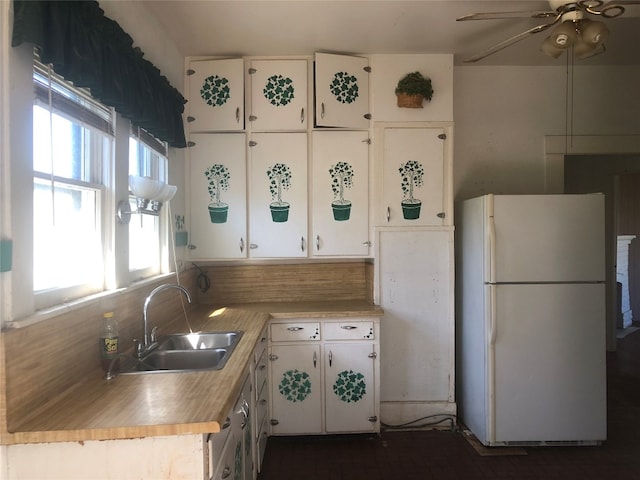 kitchen with ceiling fan, white cabinetry, white fridge, and sink