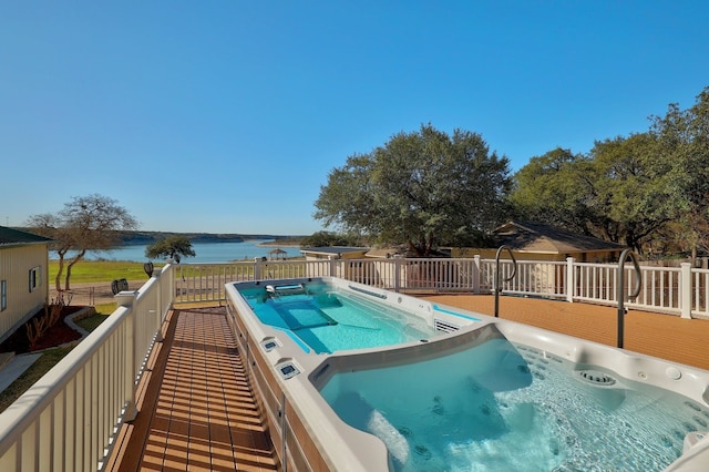 view of pool with a water view and a hot tub