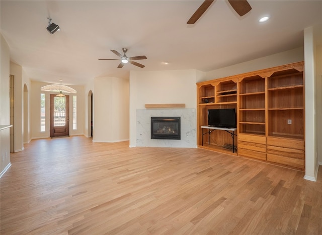 unfurnished living room featuring light hardwood / wood-style flooring, ceiling fan, and a fireplace