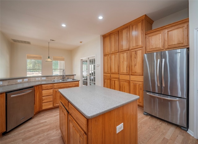 kitchen with french doors, pendant lighting, a kitchen island, appliances with stainless steel finishes, and light wood-type flooring