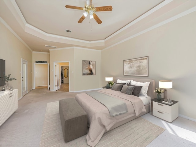 carpeted bedroom with crown molding, a tray ceiling, and ceiling fan