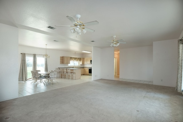 unfurnished living room with ceiling fan with notable chandelier and light colored carpet