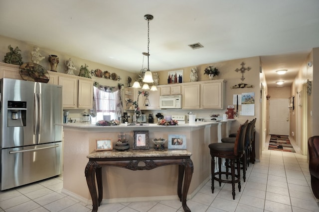 kitchen with a breakfast bar area, white appliances, a chandelier, and light tile floors