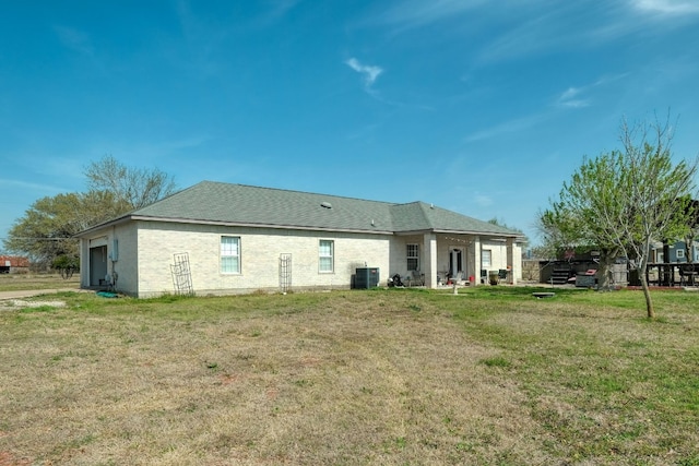 rear view of property featuring central AC unit and a yard