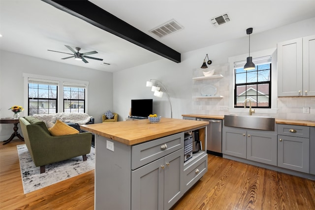 kitchen featuring pendant lighting, backsplash, gray cabinetry, sink, and butcher block countertops