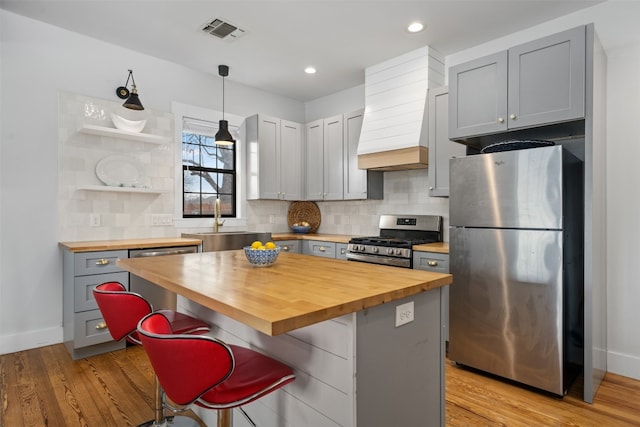 kitchen featuring wooden counters, hanging light fixtures, light hardwood / wood-style floors, and appliances with stainless steel finishes