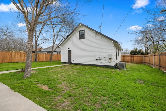 rear view of property featuring central AC unit and a lawn