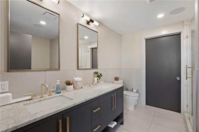 bathroom featuring dual vanity, tile flooring, toilet, and tile walls