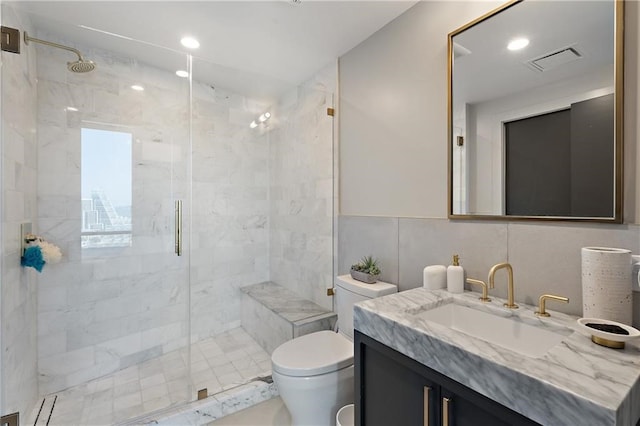 bathroom with a shower with door, oversized vanity, toilet, and tile walls