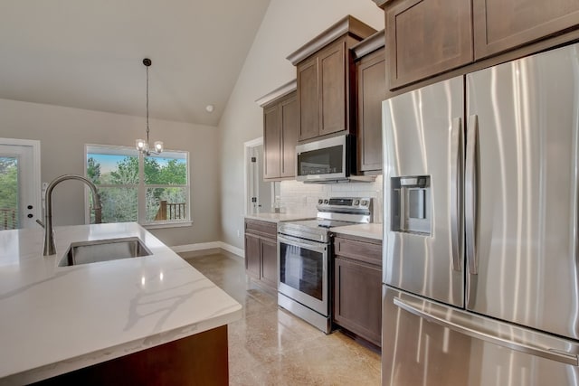 kitchen featuring sink, light stone counters, appliances with stainless steel finishes, a chandelier, and lofted ceiling