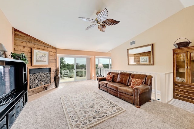 living room featuring ceiling fan, wooden walls, light colored carpet, and vaulted ceiling