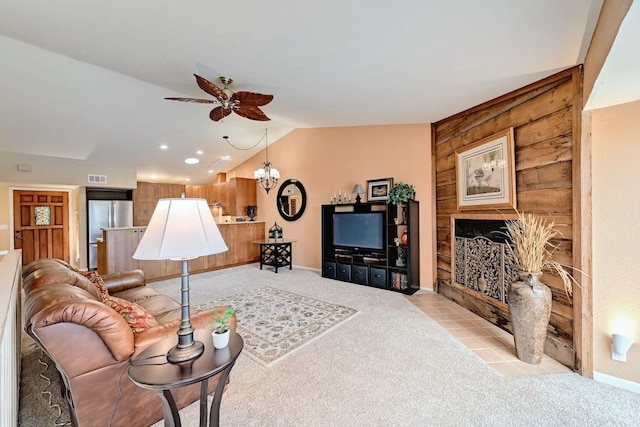 carpeted living room featuring wooden walls, lofted ceiling, and ceiling fan with notable chandelier