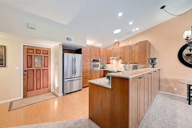 kitchen featuring light stone counters, stainless steel appliances, light wood-type flooring, backsplash, and vaulted ceiling