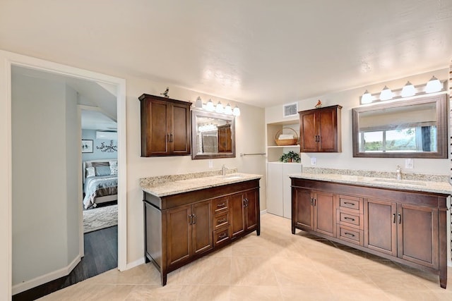 kitchen with light tile floors, light stone counters, dark brown cabinetry, and sink