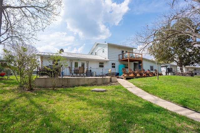 rear view of property featuring a deck and a lawn