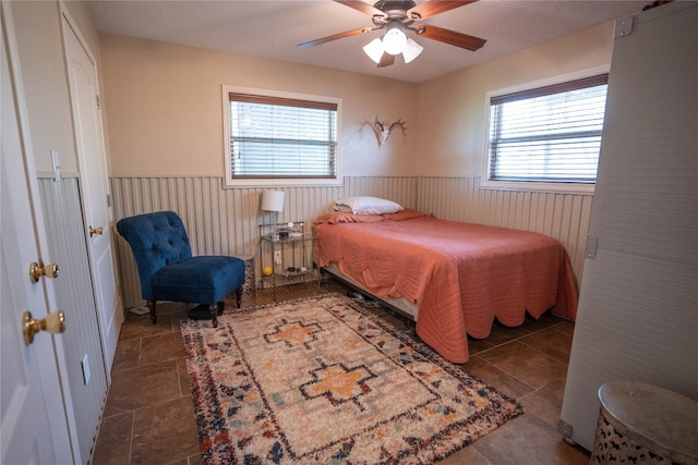 bedroom featuring multiple windows, dark tile flooring, and ceiling fan