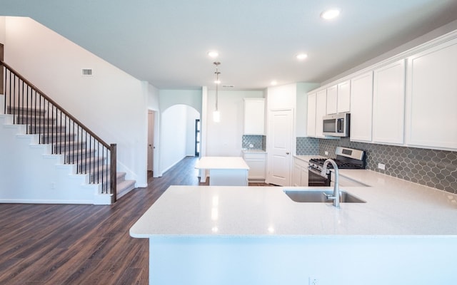 kitchen with white cabinets, stainless steel appliances, dark hardwood / wood-style floors, and light stone counters