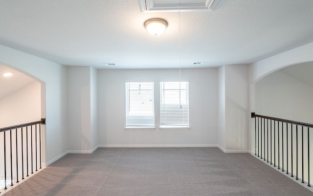 carpeted empty room featuring a textured ceiling