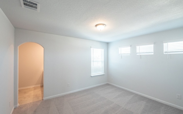 spare room featuring light carpet and a textured ceiling