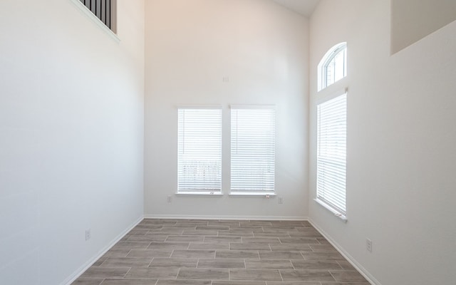 spare room featuring a towering ceiling and a healthy amount of sunlight