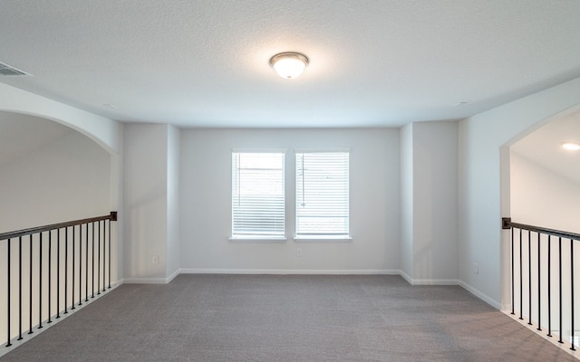 carpeted empty room featuring a textured ceiling