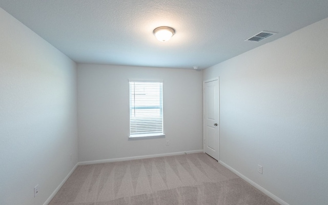 empty room with light colored carpet and a textured ceiling