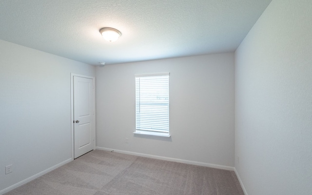 spare room with light colored carpet and a textured ceiling