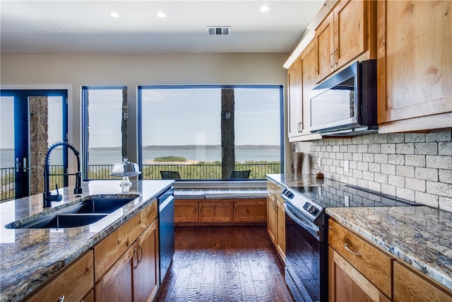 kitchen featuring dark wood-type flooring, stone countertops, black appliances, and sink