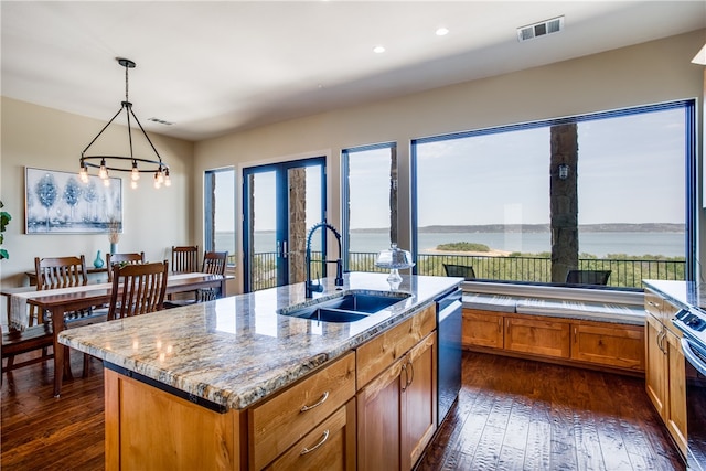 kitchen with pendant lighting, dark wood-type flooring, a water view, a kitchen island with sink, and sink