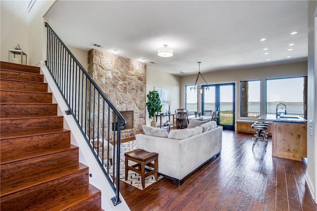 living room featuring a water view, dark hardwood / wood-style flooring, and a fireplace