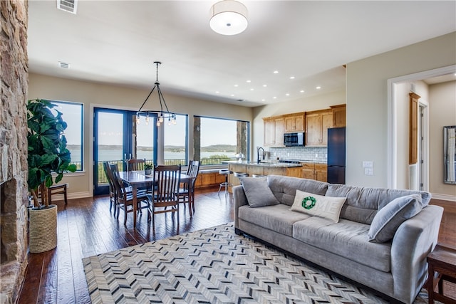 living room featuring a water view, a notable chandelier, light wood-type flooring, and a wealth of natural light