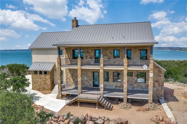 back of property with a balcony and a water view