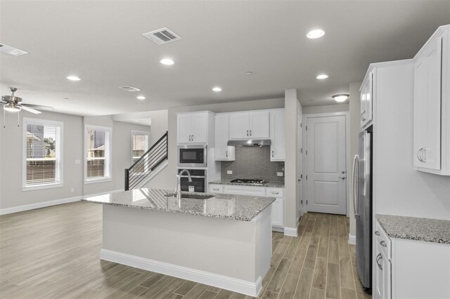 kitchen featuring appliances with stainless steel finishes, ceiling fan, an island with sink, and white cabinets