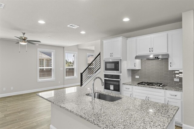 kitchen featuring ceiling fan, white cabinets, appliances with stainless steel finishes, and light hardwood / wood-style floors