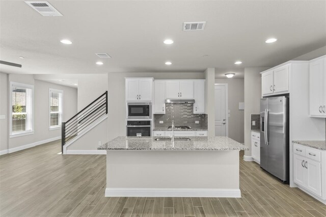 kitchen featuring white cabinets, an island with sink, and stainless steel appliances