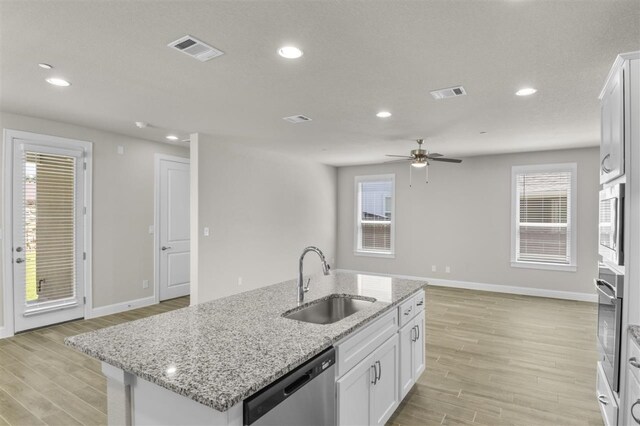 kitchen with ceiling fan, sink, light hardwood / wood-style flooring, a kitchen island with sink, and white cabinetry