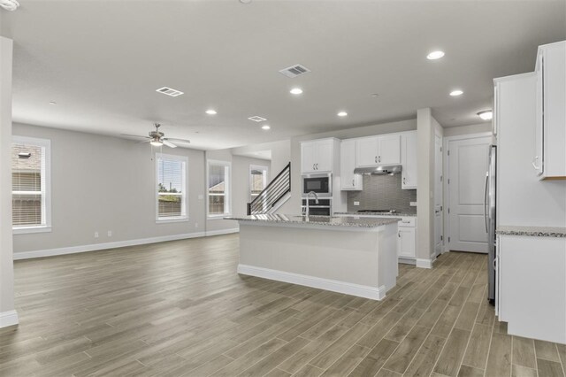 kitchen featuring ceiling fan, white cabinets, a kitchen island with sink, and light hardwood / wood-style flooring