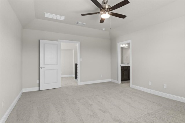 unfurnished bedroom with ensuite bath, ceiling fan, vaulted ceiling, and light colored carpet