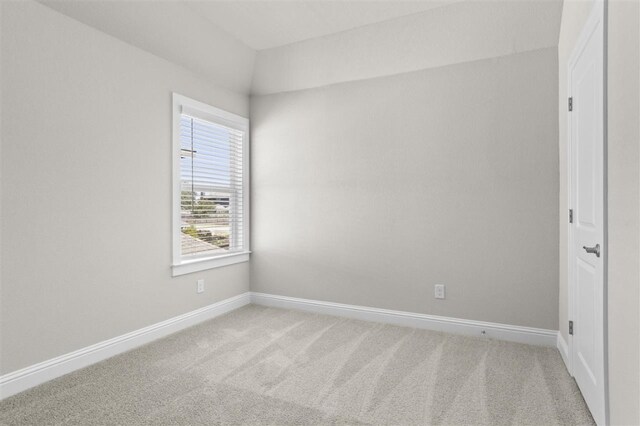 carpeted empty room with vaulted ceiling