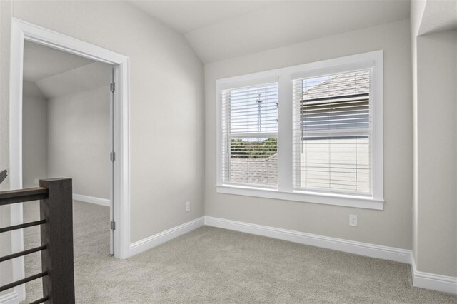 unfurnished room featuring lofted ceiling and light carpet