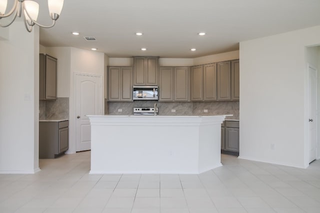 kitchen with an island with sink, white range, a notable chandelier, and tasteful backsplash