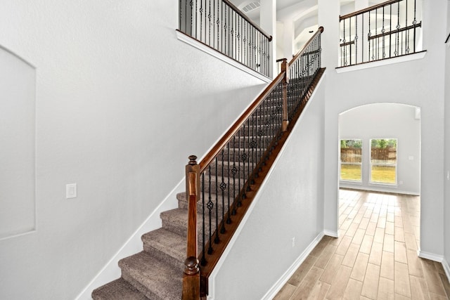 stairway with light hardwood / wood-style flooring and a high ceiling