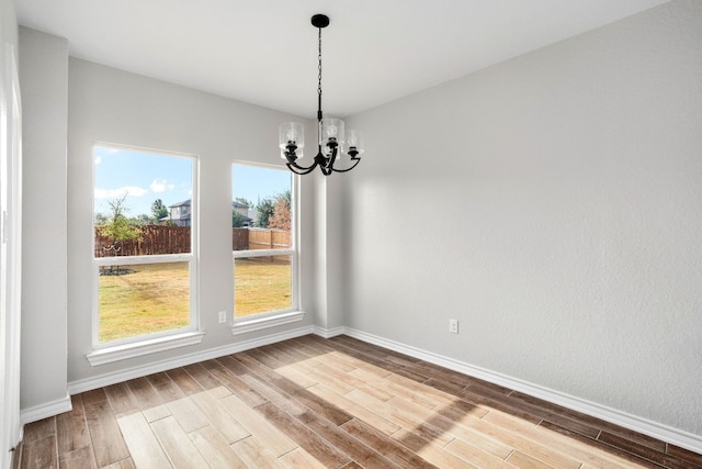 empty room featuring a chandelier and light hardwood / wood-style floors