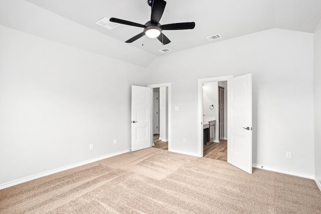 unfurnished bedroom with ensuite bath, ceiling fan, vaulted ceiling, and light colored carpet