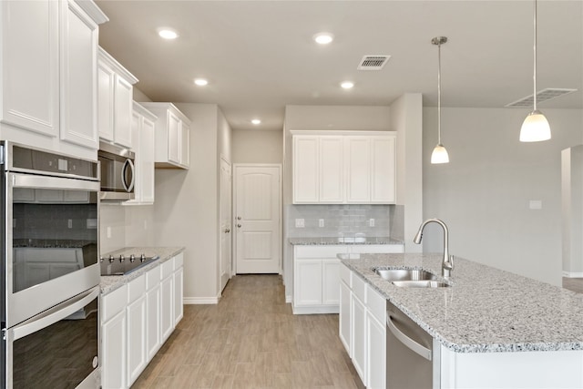 kitchen with stainless steel appliances, light hardwood / wood-style flooring, white cabinetry, backsplash, and sink